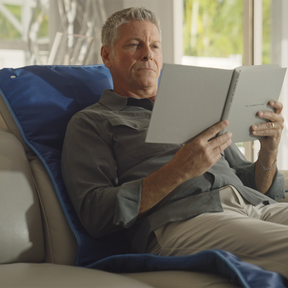 Man reading while reclining on the PureWave full-body mat